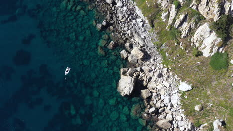 Boat-along-Porquerolles-coastline-aerial-top-shot-cliffs-rocks-and-blue-sea